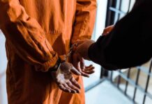 Pentagon Plans Public Execution Prisoner in orange jumpsuit handcuffed by officer