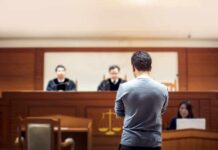 Gym Coach’s Sick Ruse Exposed defendant stands before judges in a courtroom