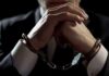 Inside Job: CIA Gold Cache Uncovered Businessperson in handcuffs with hands clasped