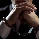 Businessperson in handcuffs with hands clasped