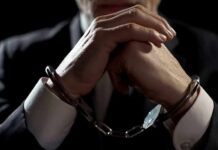 Inside Job: CIA Gold Cache Uncovered Businessperson in handcuffs with hands clasped