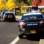 Felony Heat After Car Targets Journalist Police cars with lights on near school buses on a city street
