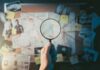 FBI Nails Alleged School Massacre Coach Hand holding magnifying glass over investigation board