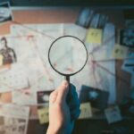 FBI Nails Alleged School Massacre Coach Hand holding magnifying glass over investigation board