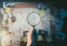 FBI Nails Alleged School Massacre Coach Hand holding magnifying glass over investigation board