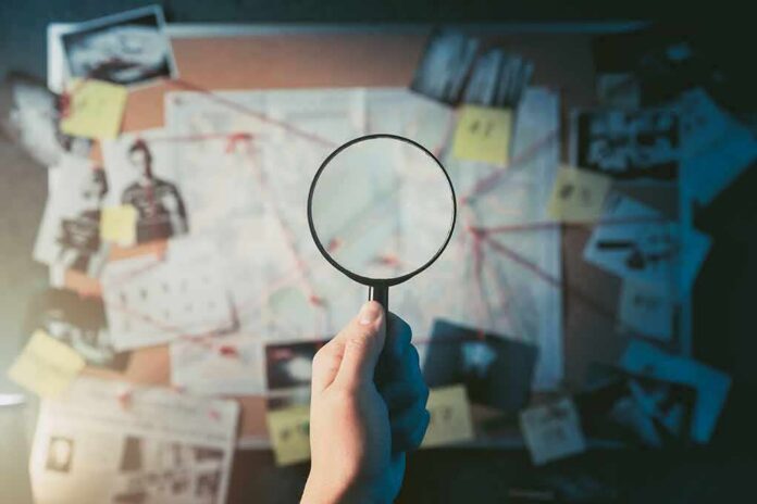 Hand holding magnifying glass over investigation board