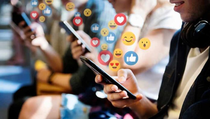 shutterstock_1338120284-1 people using smartphones with social media reactions