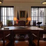 Executive office with large wooden desk and flags