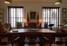 Executive office with large wooden desk and flags