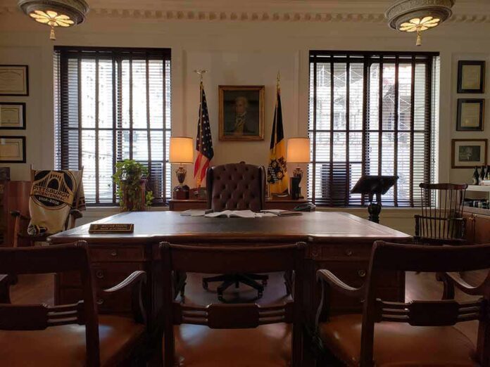 shutterstock_1454852138 Executive office with large wooden desk and flags