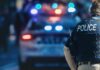 Night Stalker With “Rifle” Evades Cops police officer in vest near patrol car with flashing lights