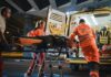 Paramedics load a patient on a stretcher into an ambulance at night