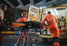 Face Scorched in Street Ambush Paramedics load a patient on a stretcher into an ambulance at night