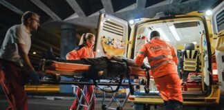 Paramedics load a patient on a stretcher into an ambulance at night