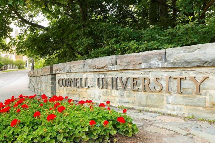 shutterstock_2015792822 Cornell University stone entrance sign with red flowers