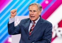 Texas Scores Gigantic DHS Payout man in suit speaking on stage with raised fist