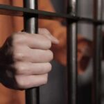hands gripping prison bars