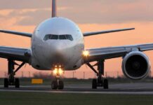 Front view of a commercial airplane on runway at sunset