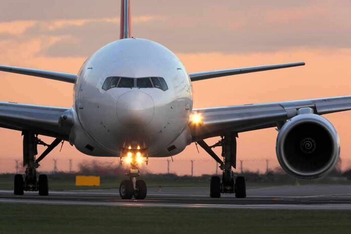 shutterstock_555148006 Front view of a commercial airplane on runway at sunset