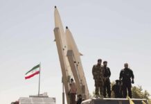 IRGC Fingered at U.S. Bomber Base Soldiers stand beside large missiles at an outdoor display